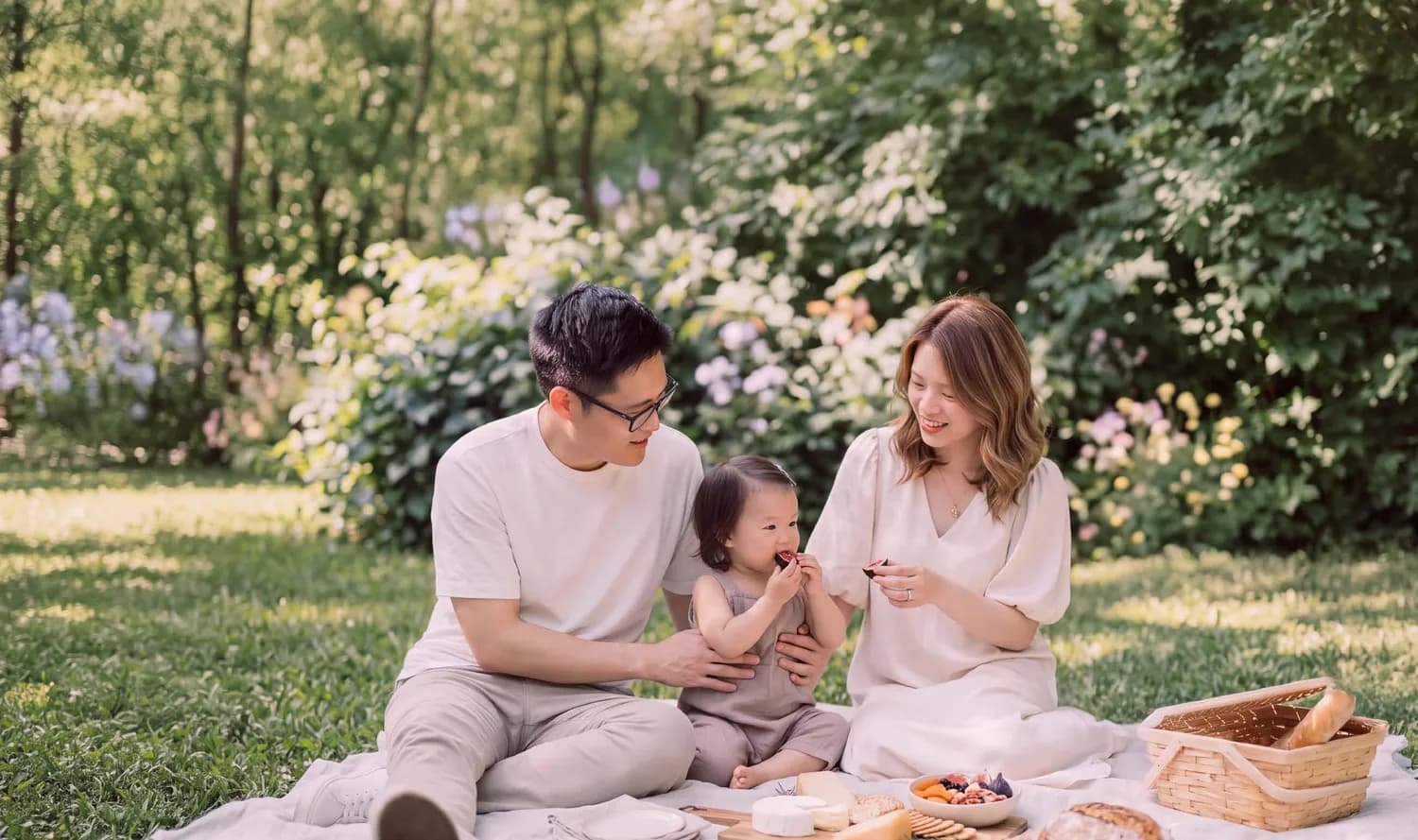 Gia đình ba người dã ngoại trên thảm cỏ giữa vườn hoa